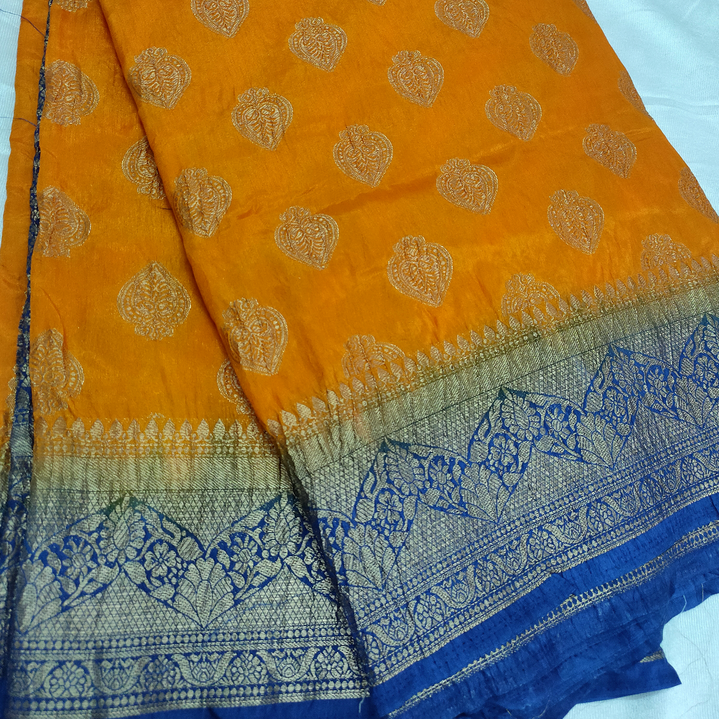 Orange fabric with gold patterns and blue border on a white background