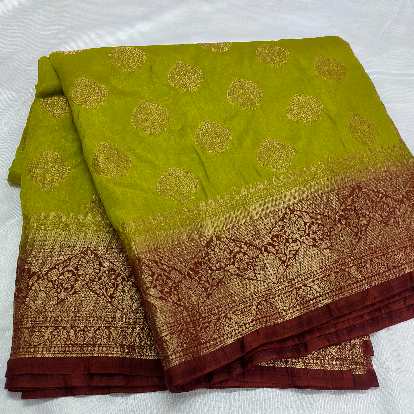 Green and brown saree with intricate patterns on a white background